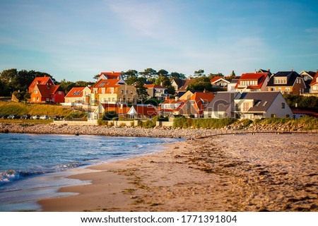 Beautiful Houses in typical yellow color on the beach with sea view during colorful sunset. Denmark, North Sea