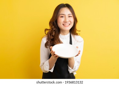 Beautiful housewife holding plate isolated on golden background