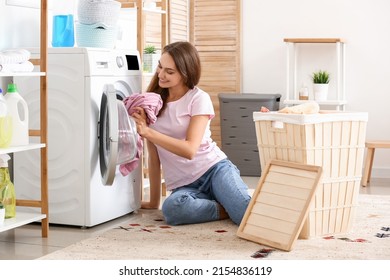 Belle femme au foyer mettant le linge sale dans la machine à laver à la maison