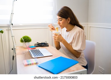 Beautiful Hungry Woman Eating Lunch At Her Office Desk While Working From Home 