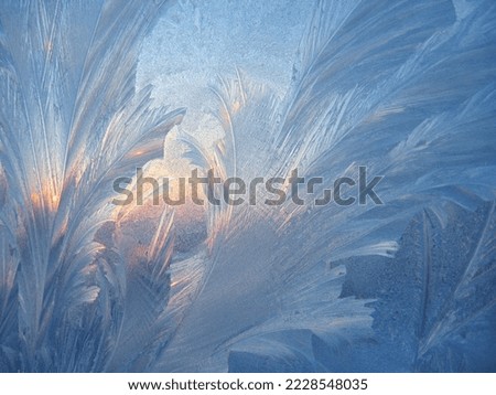 Beautiful ice pattern and sunlight closeup on window glass early in the morning, natural winter background
