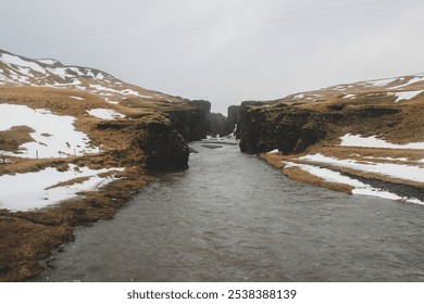 Beautiful Icelandic canyon with a winding river, mossy cliffs, and patches of snow, capturing the rugged and serene winter landscape. Perfect for travel, nature, and adventure projects. - Powered by Shutterstock