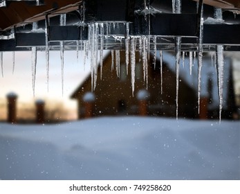 Beautiful Icicles On A Background Of A Country House And Snow Snowdrift. Snowing, Winter