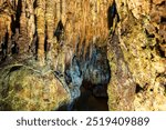 Beautiful illuminated stalactites and rock formations inside the Dragons Cave in Kastoria, Greece, showcasing natural geological wonders.