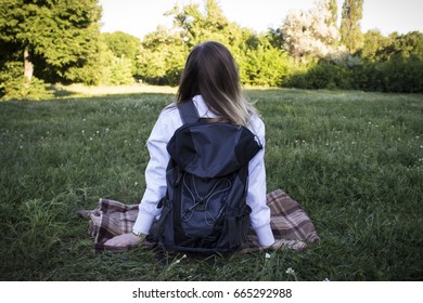 Beautiful image of a girl with a backpack sitting on the grass.  - Shutterstock ID 665292988