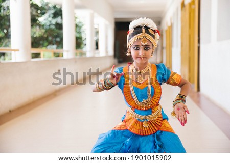 Beautiful Indian, Asian Dancing Girl with traditional dress-wearing gold jewelries-blue and orange color dress