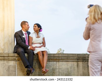 Beautiful Indian Bride And Caucasian Groom,  After Wedding Ceremony. Happy Couple In Love, Celebrating Wedding. Making Photosession By Photographer