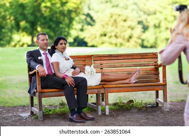 Beautiful Indian Bride And Caucasian Groom,  After Wedding Ceremony. Happy Couple In Love, Celebrating Wedding. Making Photosession By Photographer