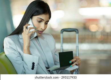 beautiful indian business woman talking on cell phone and checking air ticket