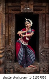 Beautiful Indian classical odissi dancer posing in front of Mukteshvara temple with sculptures in bhubaneswar, odisha ,India
