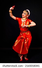 Beautiful Indian dancer in bright traditional clothes in the pose of Indian dance on a black background. Indian classical dance bharatanatyam.