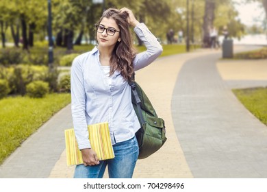 Beautiful Indian girl, student, in the campus park. Attractive young woman with books and a backpack. - Shutterstock ID 704298496