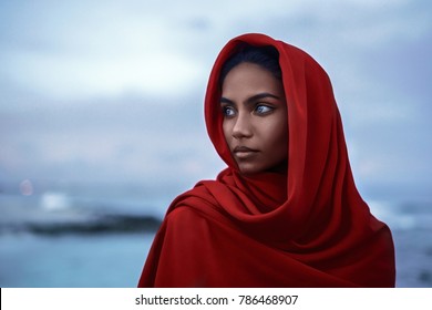 Beautiful indian woman with blue eyes and red paranja in the twilight