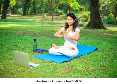 Beautiful Indian Woman Doing Breathing Yoga Exercise In The Park While Using Laptop For Online Class Or Virtual Tutorials, Asian Female Meditation Pose, Healthcare. Online Learning