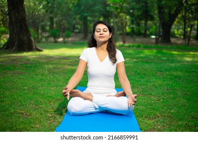 Beautiful Indian Woman Doing Breathing Yoga Exercise In The Park, Asian Female Meditation Pose, Healthcare. Copy Space