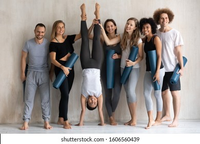 Beautiful Indian Woman Doing Handstand Exercise, Portrait Smiling Diverse People With Mats, Fitness Center Staff In Yoga Studio, Posing For Photo At Grey Wall Background, Having Fun After Training