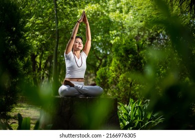 Beautiful indian woman doing yoga exercise while sitting in the green forest nature, Asian female meditation pose, Culture and traditions of India. yogi, copy space - Powered by Shutterstock