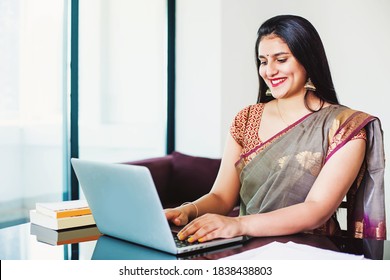 Beautiful Indian woman in a saree working on her laptop from home office