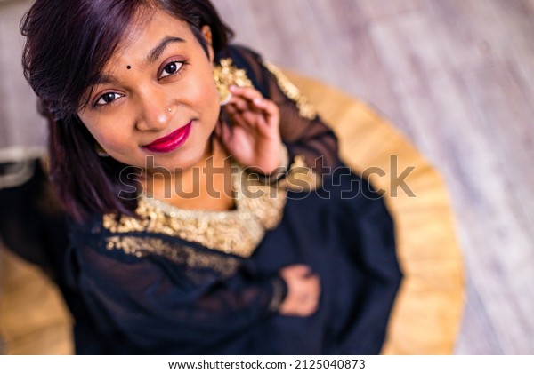 Beautiful Indian woman in traditional sari\
dress looking at camera bindi on the\
forehead