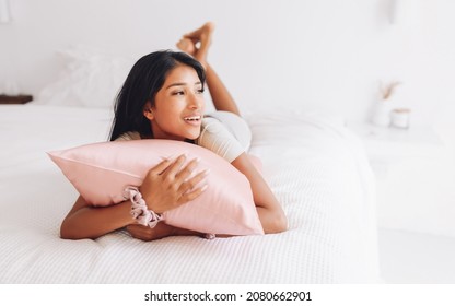 Beautiful Indonesian girl lying on a pink pillow with a silk pillowcase. - Shutterstock ID 2080662901