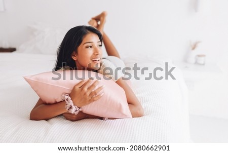 Beautiful Indonesian girl lying on a pink pillow with a silk pillowcase.