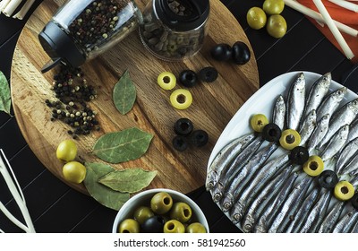 Beautiful, interesting serving on the table of the useful little fish sprat, condiments, olives and decor. The view from the top