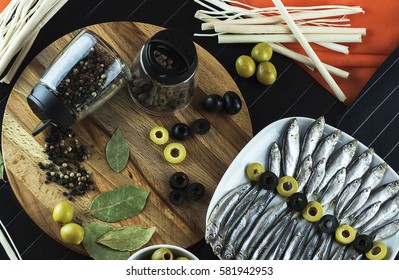 Beautiful, interesting serving on the table of useful, tasty little fish sprat, condiments, olives and decor. The view from the top