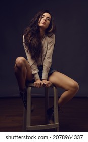 Beautiful Intimate Young Woman Full Body Studio Portrait Sit On Stool Against Grey Background.