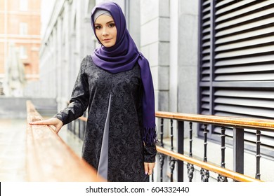 Beautiful Islamic woman in traditional oriental clothes standing on a city street