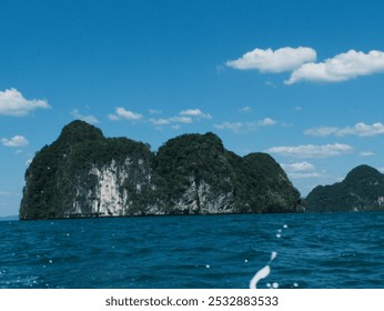 A beautiful island with a blue sky and a calm ocean. The island is surrounded by water and has a rocky shoreline. The sky is clear and the sun is shining brightly - Powered by Shutterstock