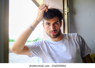 Beautiful Italian Dark-haired Guy At The Window In T-shirt. High Quality Photo