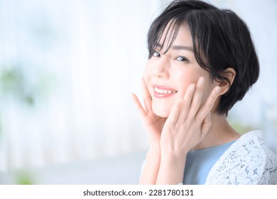 Beautiful Japanese woman with hand on face and smile, easy to use for beauty. Copy space and front blur