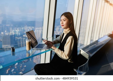 Beautiful Japanese woman successful manager is thinking what to write in text message on cell telephone,while is sitting with portable net-book in coffee shop in building of the company where she work - Shutterstock ID 484939531