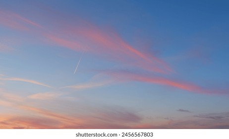 Beautiful jet contrail as airplane streaks across sky. Pink orange red blue clear sunset or sunrise sky, white and pink soft gradient clouds. Timelapse. - Powered by Shutterstock