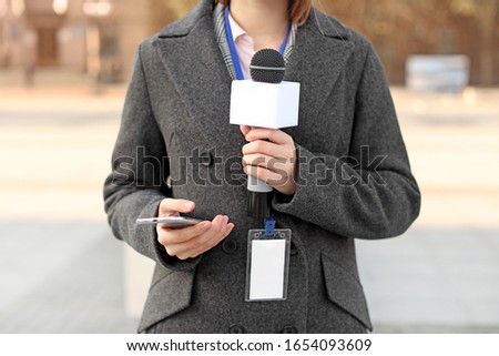 Beautiful journalist with microphone outdoors