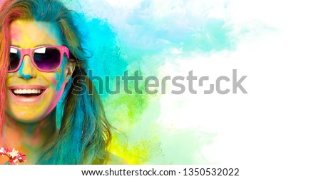 Beautiful joyful young woman celebrating Holi festival of colors, covered in rainbow colored powder with pink sunglasses smiling at camera. Gorgeous party girl having fun with colorful powder