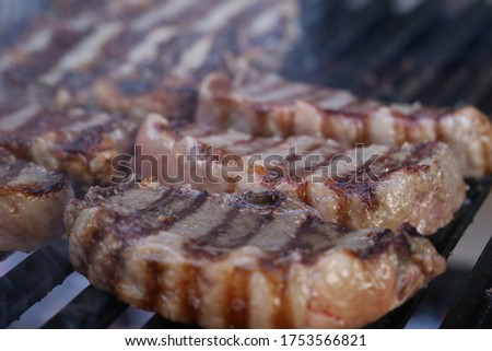 Beautiful juicy Picanha close up with grill marks on top of the grill with glowing coal at the bottom. Close up side view