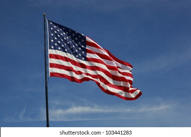 Beautiful jumbo American flag on a flag pole flying against a blue sky
