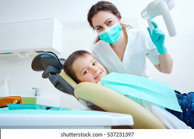 Beautiful Kid Boy Smiling In Dentist's Chair The Office Treats Teeth. Doctor Mask And Child Looks At Camera.