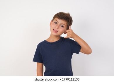 Beautiful Kid Boy Wearing Casual T-shirt Standing Over Isolated White Background Smiling Doing Phone Gesture With Hand And Fingers Like Talking On The Telephone. Communicating Concepts.