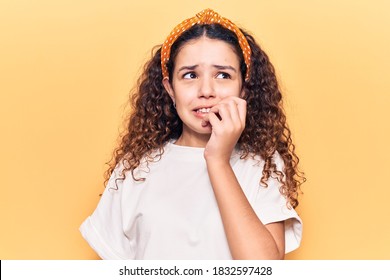 Beautiful kid girl with curly hair wearing casual clothes looking stressed and nervous with hands on mouth biting nails. anxiety problem. 