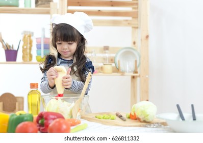 Beautiful Kid Making Vegetable Salad In The Kitchen