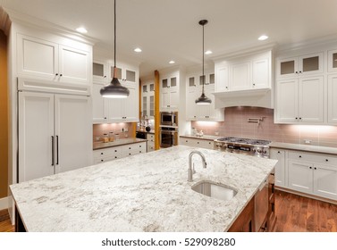 Beautiful Kitchen Interior With Island, Sink, Cabinets, And Hardwood Floors In New Luxury Home. Large Island With Sink Provides Ample Room For Food Preparation.