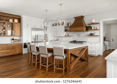Beautiful Kitchen in New Luxury Home: White Cabinets Contrast Against Rich Hardwood Accents and Floor. Features Huge Kitchen Island