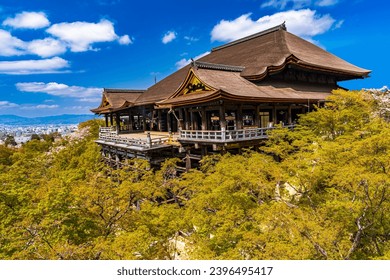 Beautiful Kiyomizu-dera Temple with wooden stage that juts out from its main hall, 13 meters above the hillside and blur foreground of green foliage, in Kyoto, Japan - Powered by Shutterstock