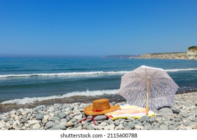 Beautiful Kourion beach on a clear sunny day, hat, towel and lace umbrella in the foreground, Limassol, Cyprus.