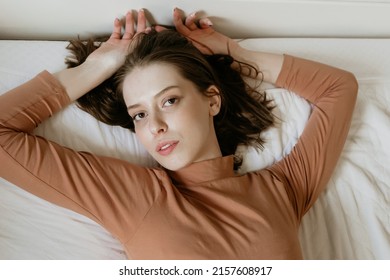 The Beautiful L Top Shot Of A Female Model With Brown Hair Posing On A White Bed In The Bedroom