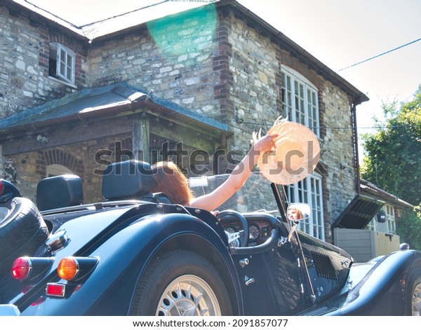 A beautiful lady enjoys her summer\
holidays with her brand new luxury British car in the\
UK.