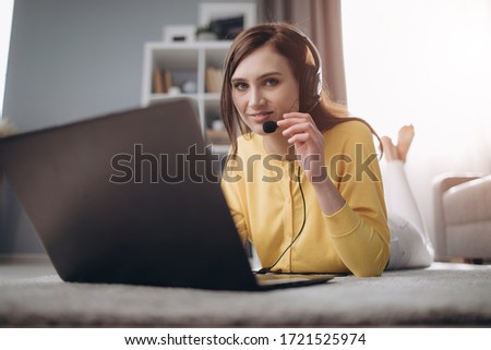 Beautiful lady in headset lying on floor with opened laptop