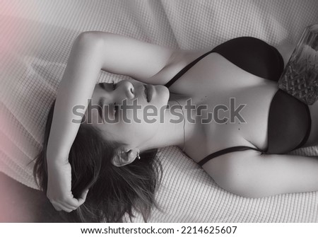 Beautiful lady laying down on bed,raise hand over her head,portrait model posing.vintage art tone,blueey light around